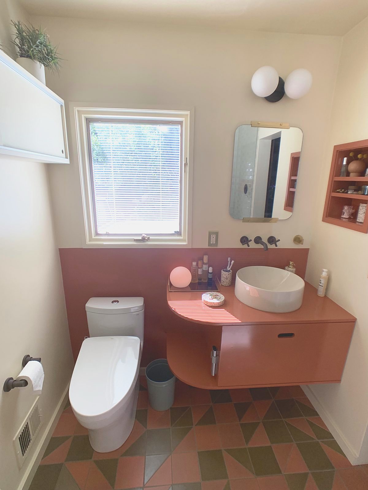 Powder room with curved clay-red floating vanity and patterned tile floor
